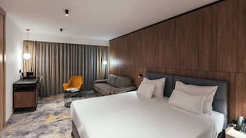 Una habitación de hotel moderna con una cama grande, un escritorio, una silla y un sofá.