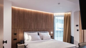 Ein modernes Hotelzimmer mit einem großen Bett, einem Schreibtisch und einem Fernseher.