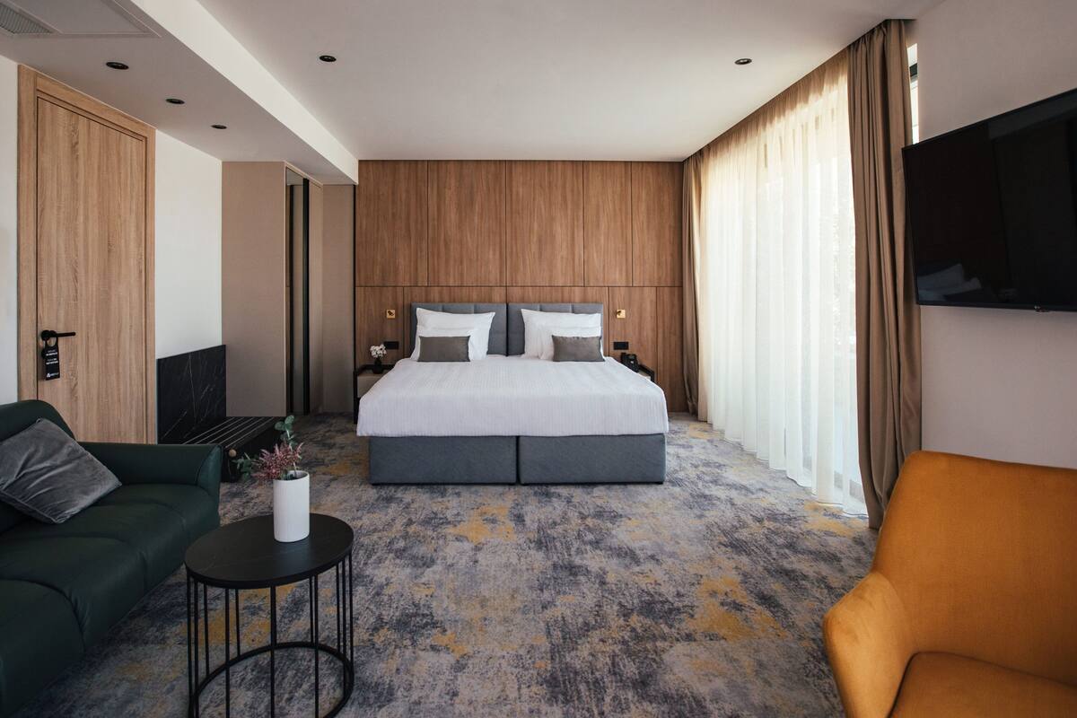 Ein modernes Hotelzimmer mit einem großen Bett, einer Couch, einem kleinen Tisch und einem Fernseher.