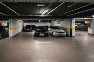 Garagem subterrânea com vários níveis e diversos carros estacionados em vagas demarcadas.