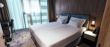 Una habitación de hotel con una cama grande, un escritorio y una silla.