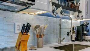 A modern kitchen with a white countertop, a built-in sink, and a knife block. - Cozy King Blue H2O Staycation , Stock Tank Pool, Hot Tub, Fire Pit Pets OK! (Winston-Salem)