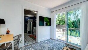 A modern kitchen with a refrigerator, a dining area with a table and chairs, and a large sliding glass door leading to an outdoor patio with chairs. - Cozy King Blue H2O Staycation , Stock Tank Pool, Hot Tub, Fire Pit Pets OK! (Winston-Salem)