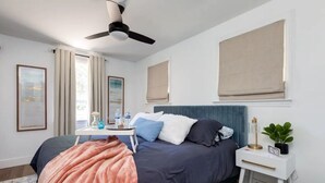 A bedroom with a bed, bedside table, nightstand, and a ceiling fan. - Cozy King Blue H2O Staycation , Stock Tank Pool, Hot Tub, Fire Pit Pets OK! (Winston-Salem)