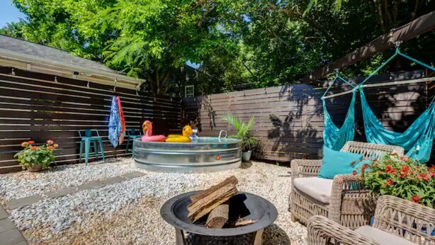 A backyard with a fire pit, wicker furniture, a hot tub, and a hammock. - Cozy King Blue H2O Staycation , Stock Tank Pool, Hot Tub, Fire Pit Pets OK! (Winston-Salem)