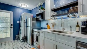 A compact kitchen with a washing machine, oven, and sink. - Cozy King Blue H2O Staycation , Stock Tank Pool, Hot Tub, Fire Pit Pets OK! (Winston-Salem)