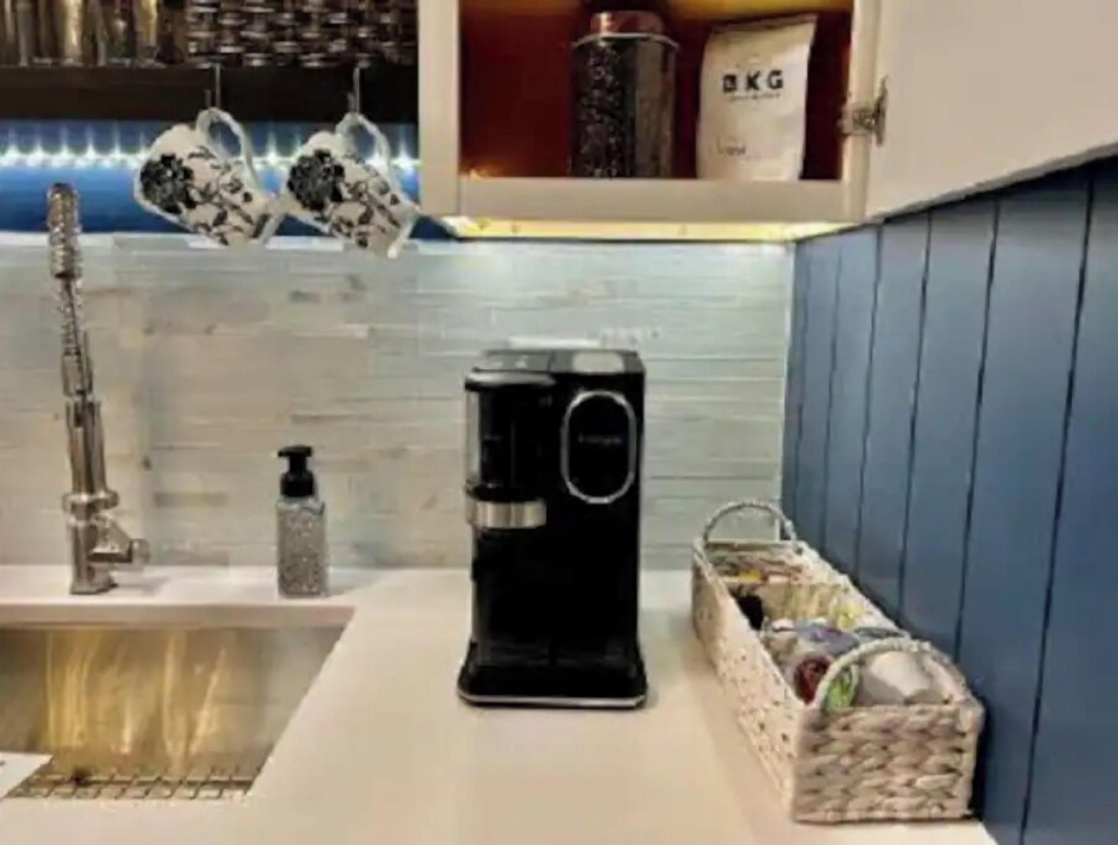 A kitchen with a coffee maker, a sink, and a spice rack.