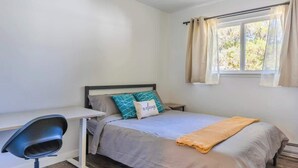 Une chambre à coucher avec un lit, un bureau et une fenêtre avec des rideaux.