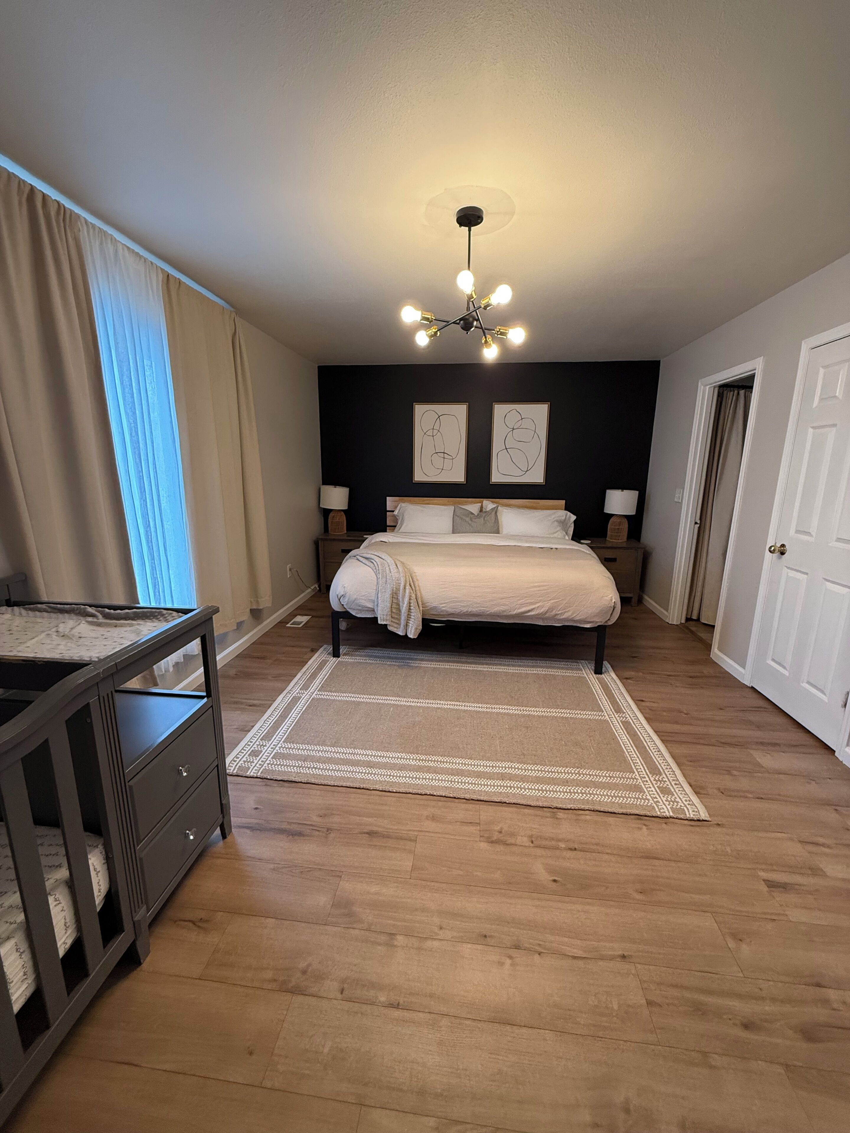 Een slaapkamer met een bed, nachtkastjes, een bureau, een vloerkleed en een plafondlamp.