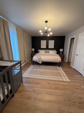 Une chambre Ă coucher comprenant un lit, des tables de chevet, un bureau, un tapis et un luminaire au plafond.
