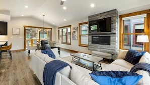 Un salón amplio con techo alto, chimenea y televisor.