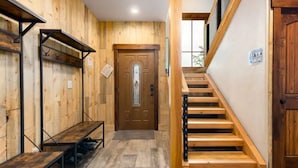 Un interior de madera con una escalera, un banco y una puerta con panel de vidrio.