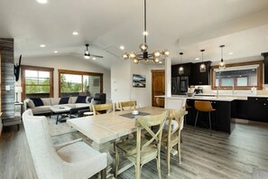 Une cuisine moderne avec des meubles de couleur sombre, un îlot central et des luminaires suspendus.