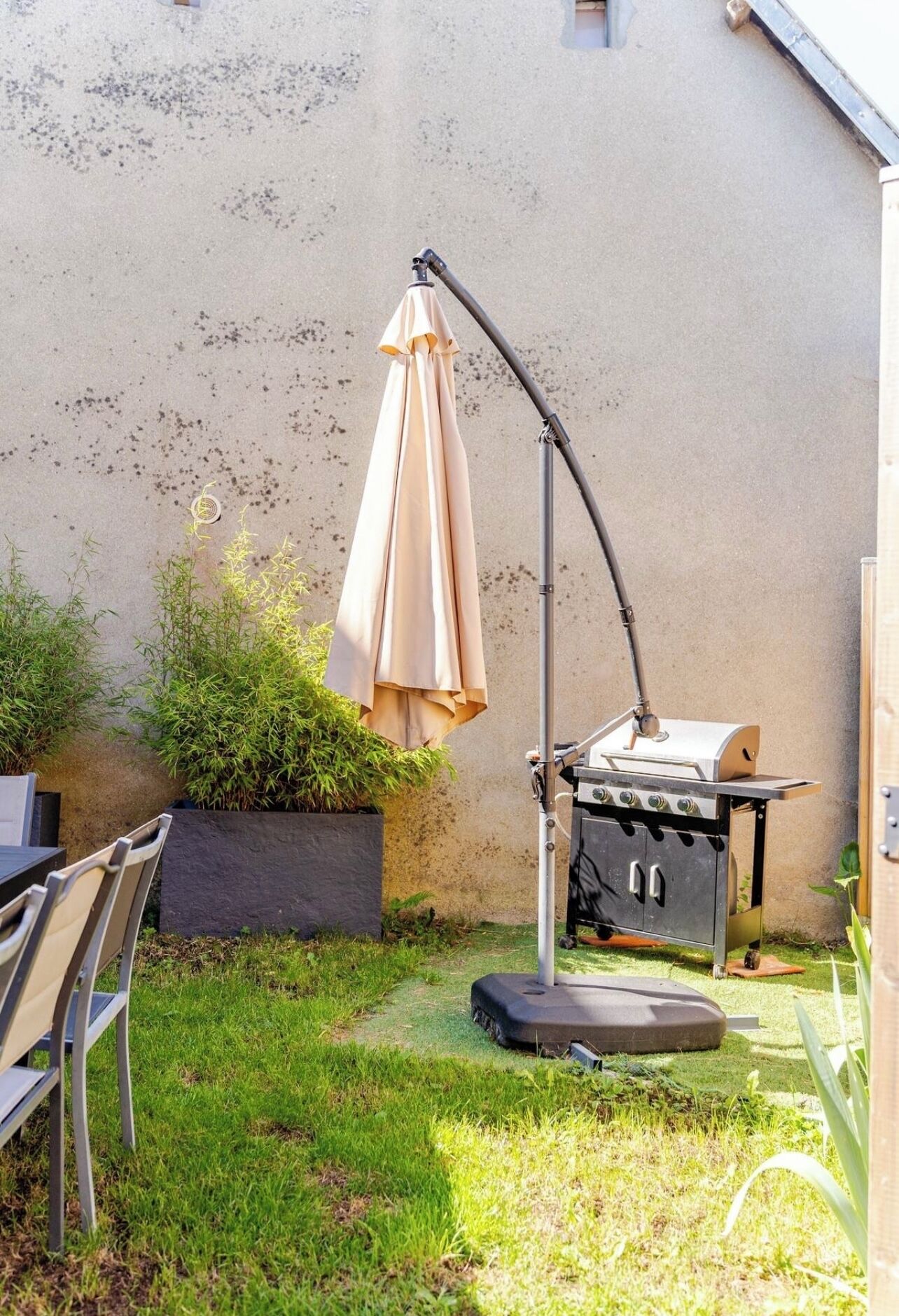 A patio area with a grill, chairs, and an umbrella.