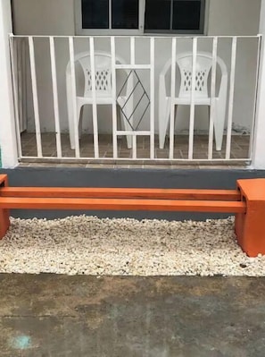 A white metal gate with a bench in front.