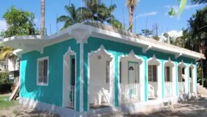 Un edificio di due piani con facciata verde acqua e bianca, diversi balconi e un piccolo portico.