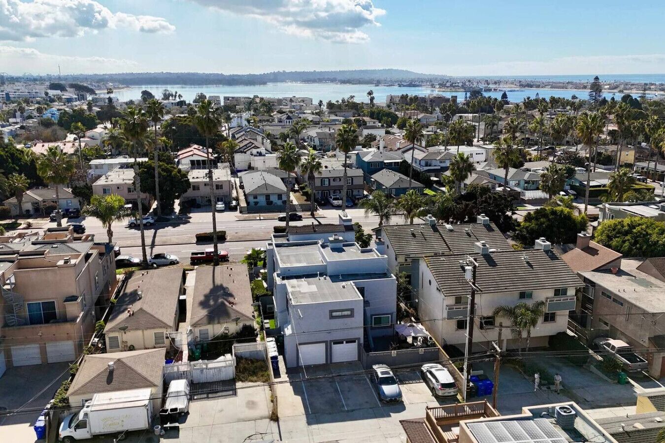 A residential area with houses, parked cars, and a clear view of the ocean.