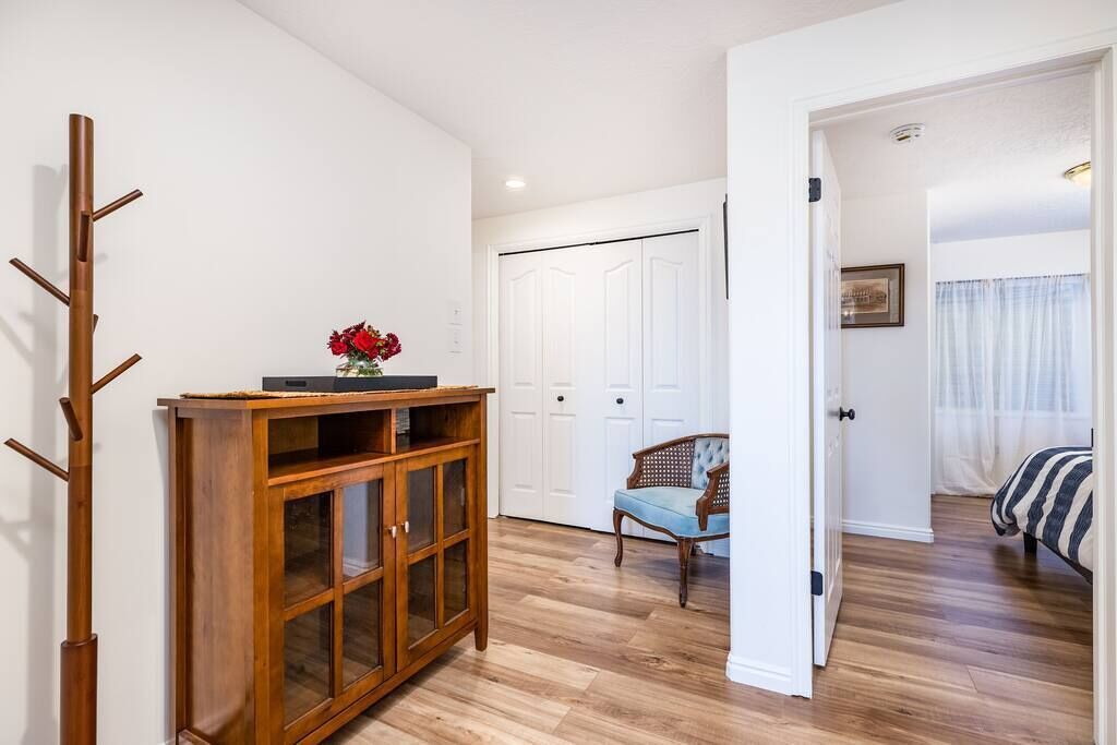 A room with a wooden cabinet, a chair, a bed, and a white door.