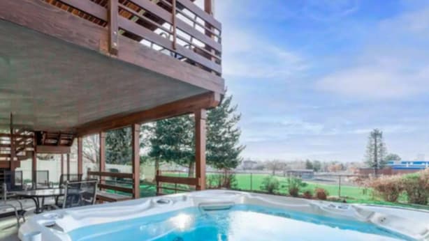 Un bain à remous avec une terrasse en bois et vue sur un parc.