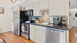 A modern kitchen with stainless steel appliances, white cabinets, and a granite countertop. - 2 bed 2 bath Rustic roost loft condo; deck 2 pools; Lake Taneycomo, & amenities  (Branson)