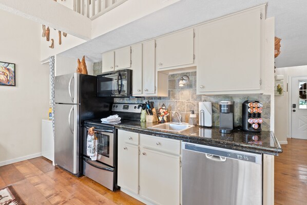 A modern kitchen with stainless steel appliances, white cabinets, and a granite countertop.