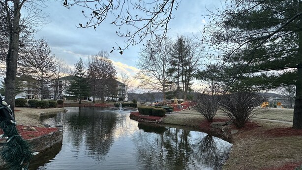 A serene park with a pond, trees, and a playground in the background. - 2 bed 2 bath Rustic roost loft condo; deck 2 pools; Lake Taneycomo, & amenities  (Branson)