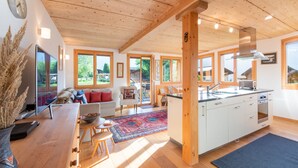 A spacious kitchen with wooden beams, a large island, and a view of the outdoors.