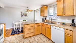 Una cocina compacta con armarios de madera, lavavajillas y un comedor con mesa y sillas.