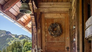 A wooden porch with a bench, a lantern, and a door with a wreath.
