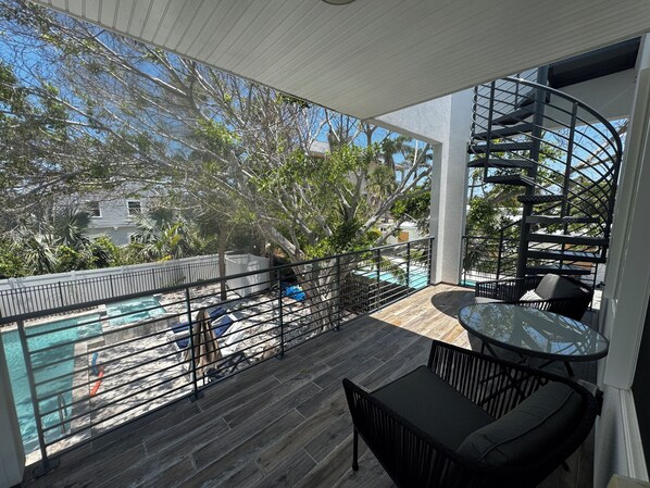 A balcony with a pool, outdoor furniture, and a spiral staircase.