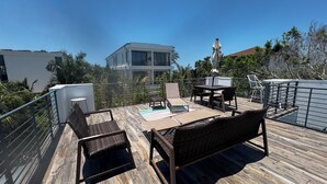 A wooden deck with outdoor furniture, a view of a modern building, and a railing. - Lido Beach House
 (Sarasota)