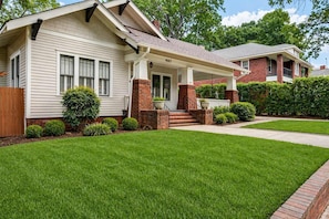 A two-story house with a front porch, brick columns, and a well-maintained lawn.