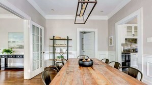 Une salle à manger spacieuse avec une longue table en bois, des chaises et un lustre moderne.