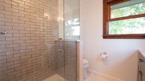 A bathroom with a glass shower enclosure, a toilet, and a window with a view of trees. - Sheldrake Solitude: "Simple and Private on Cayuga Lake (Ovid)
