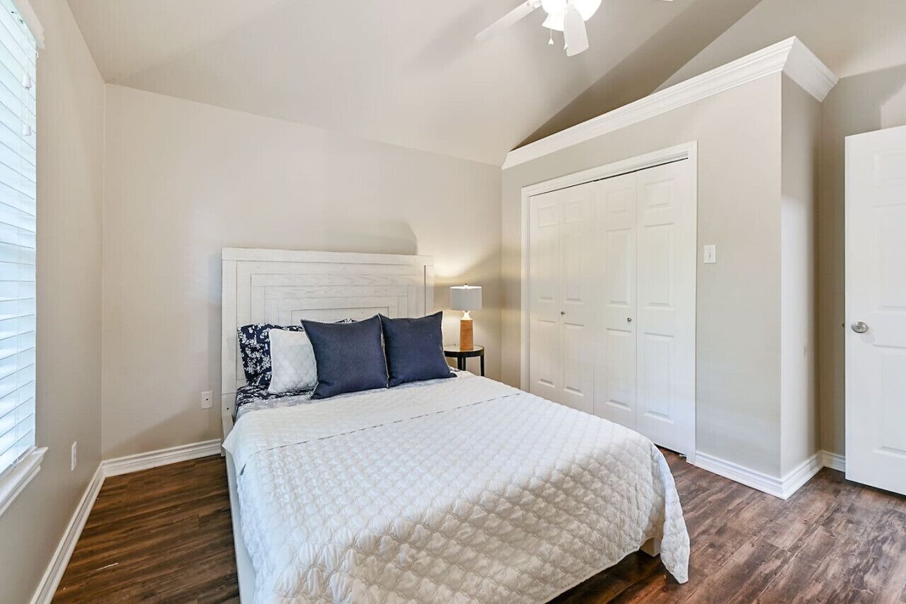 Une chambre à coucher avec un lit, une table de chevet, une lampe et une armoire.