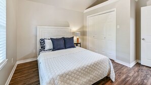 A bedroom with a bed, a nightstand, a lamp, and a closet.