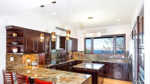A modern kitchen with dark wood cabinets, a large marble island, and pendant lighting. - 360 Splendor 207A- 2 BR Condo, Breakfast Included (360 Splendor)