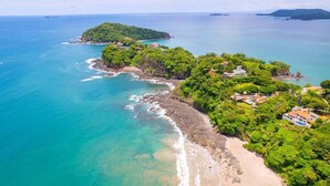 An aerial view of a coastal area with lush greenery, a beach, and several buildings. - 360 Splendor 206-Condo with Breakfast Included (360 Splendor)