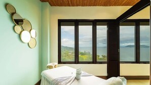 A spa room with a massage table, a wall-mounted mirror, and a large window offering a view of the landscape. - 360 Splendor 302-Condo with Breakfast Included (360 Splendor)