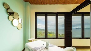 Une salle de spa équipée d’une table de massage, d’un miroir fixé au mur et d’une grande fenêtre donnant sur le paysage.