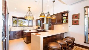 A modern kitchen with a central island, dark wooden cabinets, and pendant lighting. - 360 Splendor 308F- 3 BR Condo, Breakfast Included (360 Splendor)