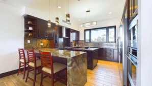 A modern kitchen with dark cabinetry, a marble island, and a large window providing natural light. - 360 Splendor 207F- 3 BR Condo, Breakfast Included (360 Splendor)