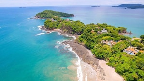 An aerial view of a coastal area with lush greenery, a beach, and several buildings. - 360 Splendor 207F- 3 BR Condo, Breakfast Included (360 Splendor)