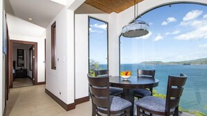 A dining area with a table and chairs, a hanging light fixture, and a view of the sea. - 360 Splendor 101F-Condo with Breakfast Included (360 Splendor)