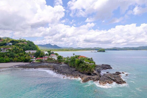 A coastal landscape with a small island, houses, and a clear sky.