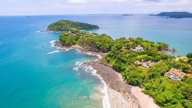 An aerial view of a coastal area with a beach, lush greenery, and several buildings. - 360 Splendor 207B-Condo with Breakfast Included (360 Splendor)