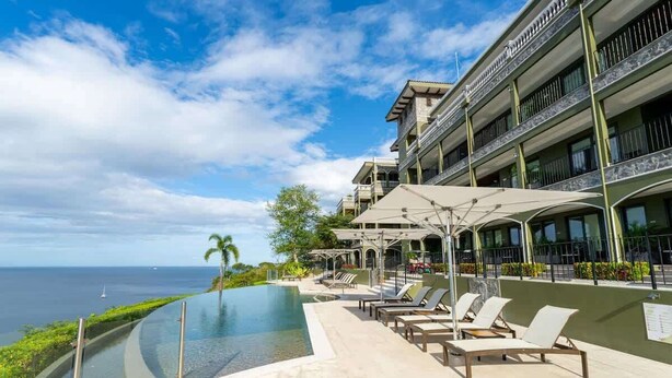 A hotel with a pool overlooking the ocean, lounge chairs, and a multi-story building with balconies. - 360 Splendor 308B-Condo with Breakfast Included (360 Splendor)