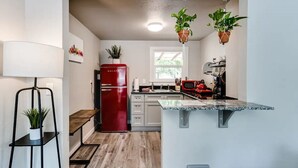 A modern kitchen with a red refrigerator, wooden flooring, and hanging plants. - Remodeled 2 bdrm duplex near the U of O (Eugene)