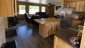 Une cuisine spacieuse avec des meubles en bois, un îlot central et un barbecue intégré.