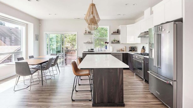 A modern kitchen with a central island, stainless steel appliances, and a dining area with chairs. - Modern Home in Walkable Neighborhood, BBQ and Patio! (Portland)